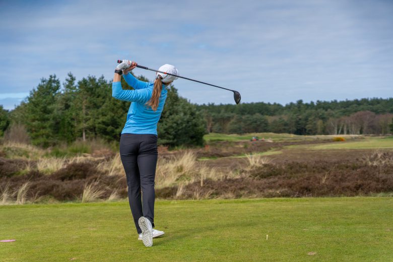 Female golfer using driver on the tee