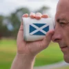 Golfer looking through PRO X rangefinder with Scotland flag plate