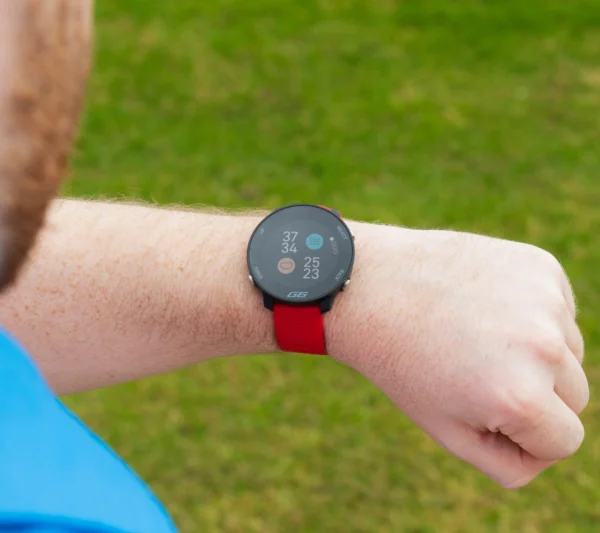 Golfer looking at red Shot Scope G6 on wrist with hazards on screen